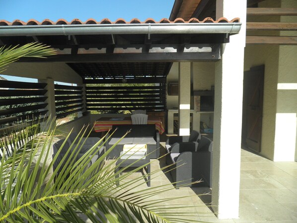 An outdoor patio area with a covered seating area, a table, and chairs. - Villa with swimming pool not overlooked near the gulf of Saint-Tropez (Taradeau)