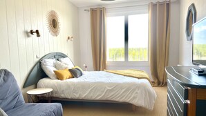 Un dormitorio con cama, sofá, televisor y ventana con cortinas.