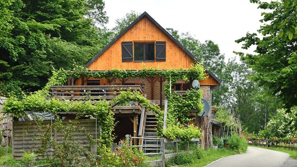 Une maison en bois avec un toit en pente, un porche à l’avant et un escalier menant à l’entrée.