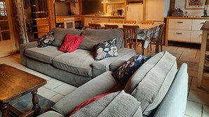 Un saló acollidor amb sofà i taula de fusta, una zona de cuina amb taula de dinar i nevera.