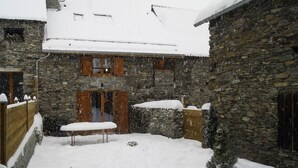Un edifici de pedra amb un teulat cobert de neu i persianes de fusta.