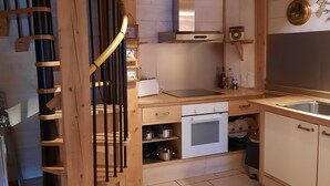 Un interior de fusta amb zona de cuina, incloent vitroceràmica, forn i armaris.
