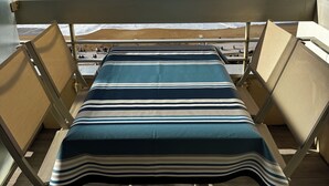 A balcony with a view of the ocean, a striped tablecloth, and cushioned chairs. - Apart 4 pers. with swimming pool and unbelievable view on ocean ! (Biarritz)