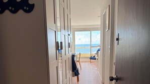 A hallway leading to a balcony with a view of the sea, wooden flooring, and a door with a handle. - Apart 4 pers. with swimming pool and unbelievable view on ocean ! (Biarritz)