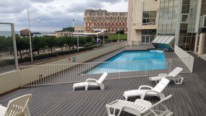 A pool area with white lounge chairs and a view of a building in the background. - Apart 4 pers. with swimming pool and unbelievable view on ocean ! (Biarritz)