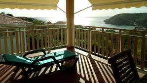 A balcony with a view of the sea, a table, and two chairs.