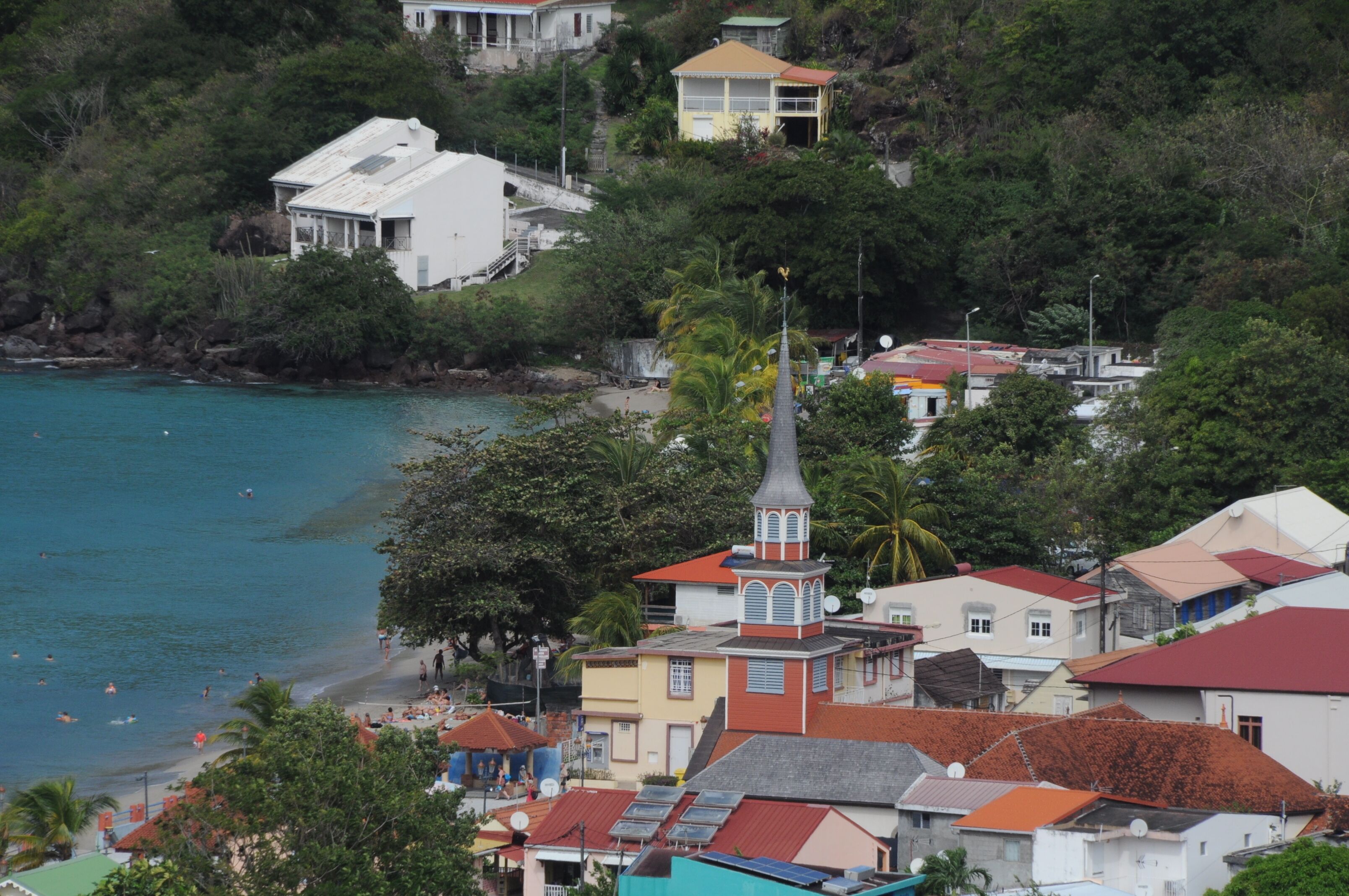 Une ville côtière avec des bâtiments, une église dotée d’un clocher imposant et une plage.