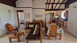 A spacious living area with a sofa, chairs, and a dining table. A kitchen is visible in the background.