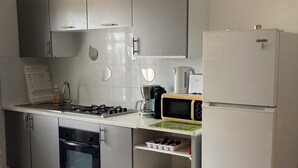 A modern kitchen with a gas stove, microwave, coffee maker, and a refrigerator.