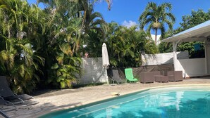 A swimming pool with lounge chairs and palm trees.