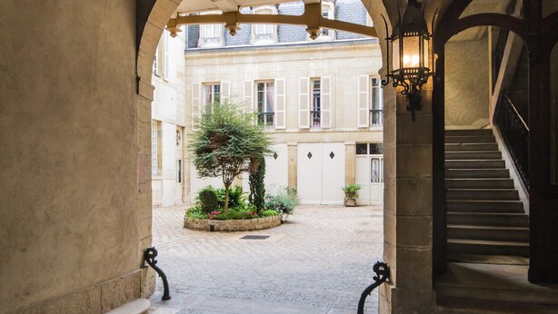 An arched corridor with a cobblestone floor leading to a courtyard with a tree and potted plants. - The Loisy - A very smart spot in the heart of Dijon for up to 4 people (Dijon)