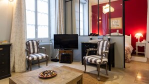 A living room with a television, two striped chairs, a coffee table with a fruit bowl, and a red accent wall. - The Loisy - A very smart spot in the heart of Dijon for up to 4 people (Dijon)