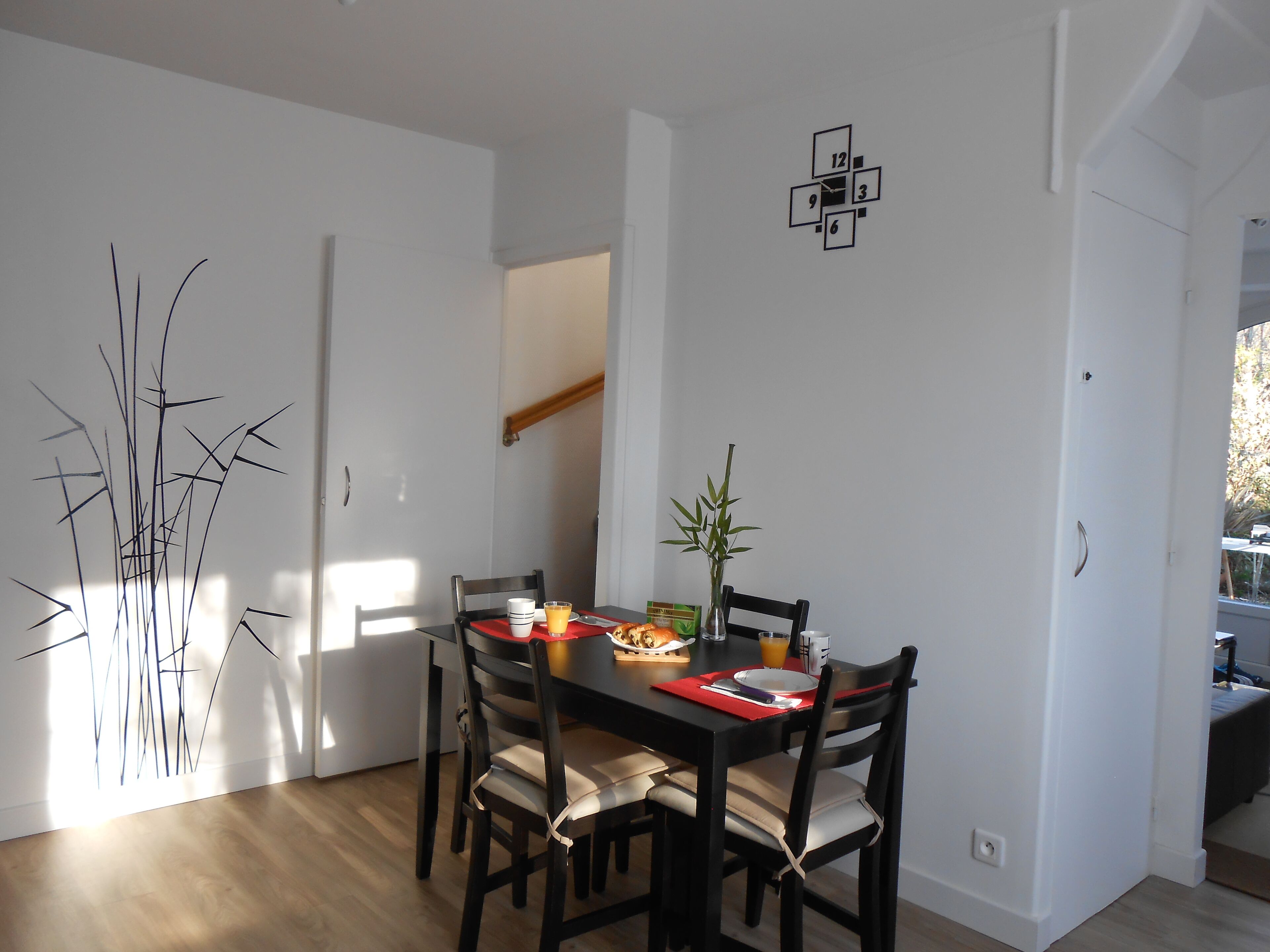 Un comedor con una mesa de madera, cuatro sillas y una planta pequeña.
