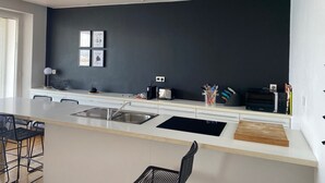 A modern kitchen with a central island, stainless steel sink, and a black backsplash. - Breathtaking sea view 1st ocean line - Contemporary decor (Saint-Jean-De-Luz)