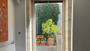 A bedroom with a bed, pillows, a bedside table, a window, and a view of the outside. - TOWNHOUSE WITH SWIMMINGPOOL - Country living in the city (Nîmes)