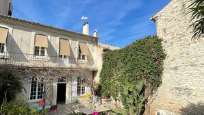 A courtyard with a pool, a wooden deck, and a stone building. - TOWNHOUSE WITH SWIMMINGPOOL - Country living in the city (Nîmes)