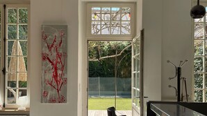 A modern kitchen with a large window, a dining area with chairs, and a patterned floor. - TOWNHOUSE WITH SWIMMINGPOOL - Country living in the city (Nîmes)