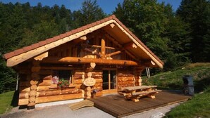 A log cabin with a wooden deck, a picnic table, and a sign indicating it's a lodge. - Sublime chalet rondins de 140 m² en lisière de forêt et ruisseau, La Bresse, wifi (La Bresse)