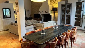 A spacious kitchen with a large dining table, wooden chairs, and a stone wall. - Farmhouse in Provence, farmhouse, private in a 7 hectares park, heated pool (L'isle-Sur-La-Sorgue)