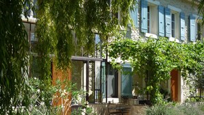 A courtyard with a stone building, a table, and chairs. - Farmhouse in Provence, farmhouse, private in a 7 hectares park, heated pool (L'isle-Sur-La-Sorgue)