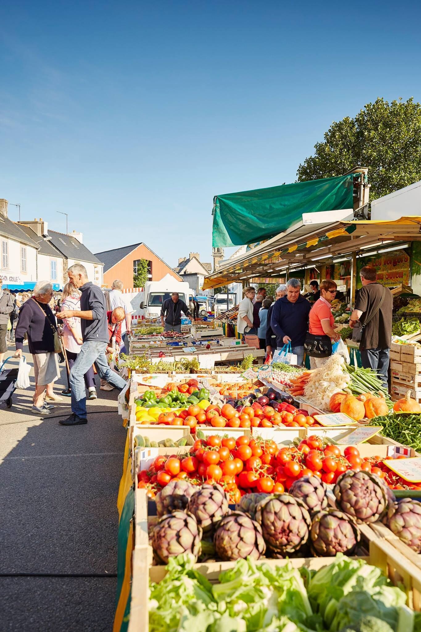 Un mercado al aire libre concurrido y varios puestos que ofrecen productos frescos.