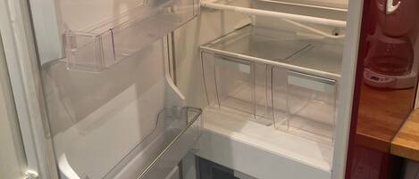 An empty refrigerator with multiple shelves and a freezer compartment.