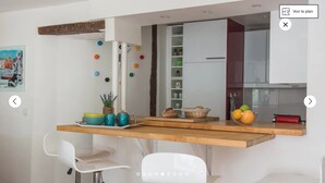 A modern kitchen with a wooden countertop, white chairs, and a variety of kitchen items.