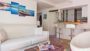 A modern living room with a white sofa, a round white chair, a wooden coffee table with magazines, and a colorful striped rug.