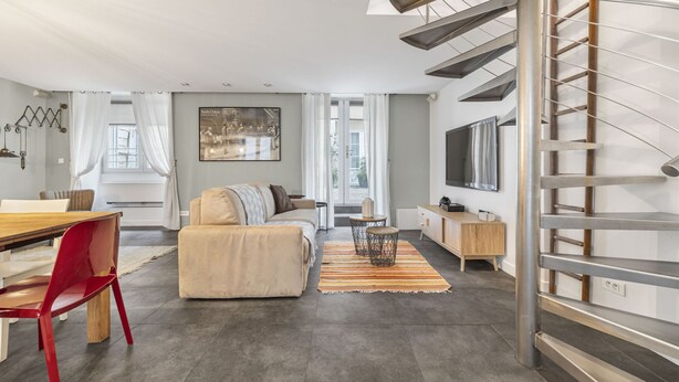 A modern living room with a sofa, a dining table, and a staircase. - Bahia, 2BR/1BA, 7 people (París)