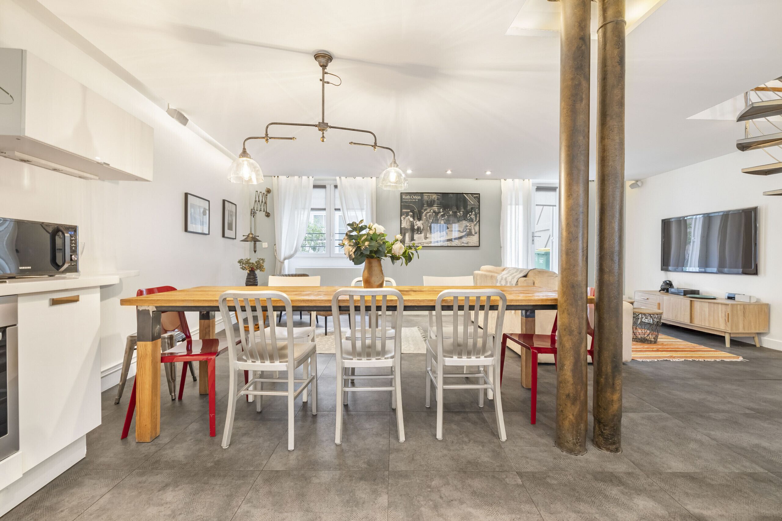 A modern kitchen with a dining area, white cabinetry, and a large wooden table.