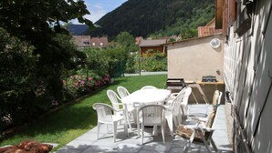 A patio with a table and chairs, surrounded by a garden with flowers and a view of a mountain. - Detached house in Metzeral for 8 to 10 people, in the Munster valley (Metzeral)