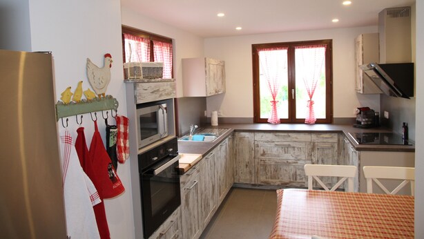 A kitchen with wooden cabinets, a refrigerator, a sink, and a window with curtains. - Detached house in Metzeral for 8 to 10 people, in the Munster valley (Metzeral)