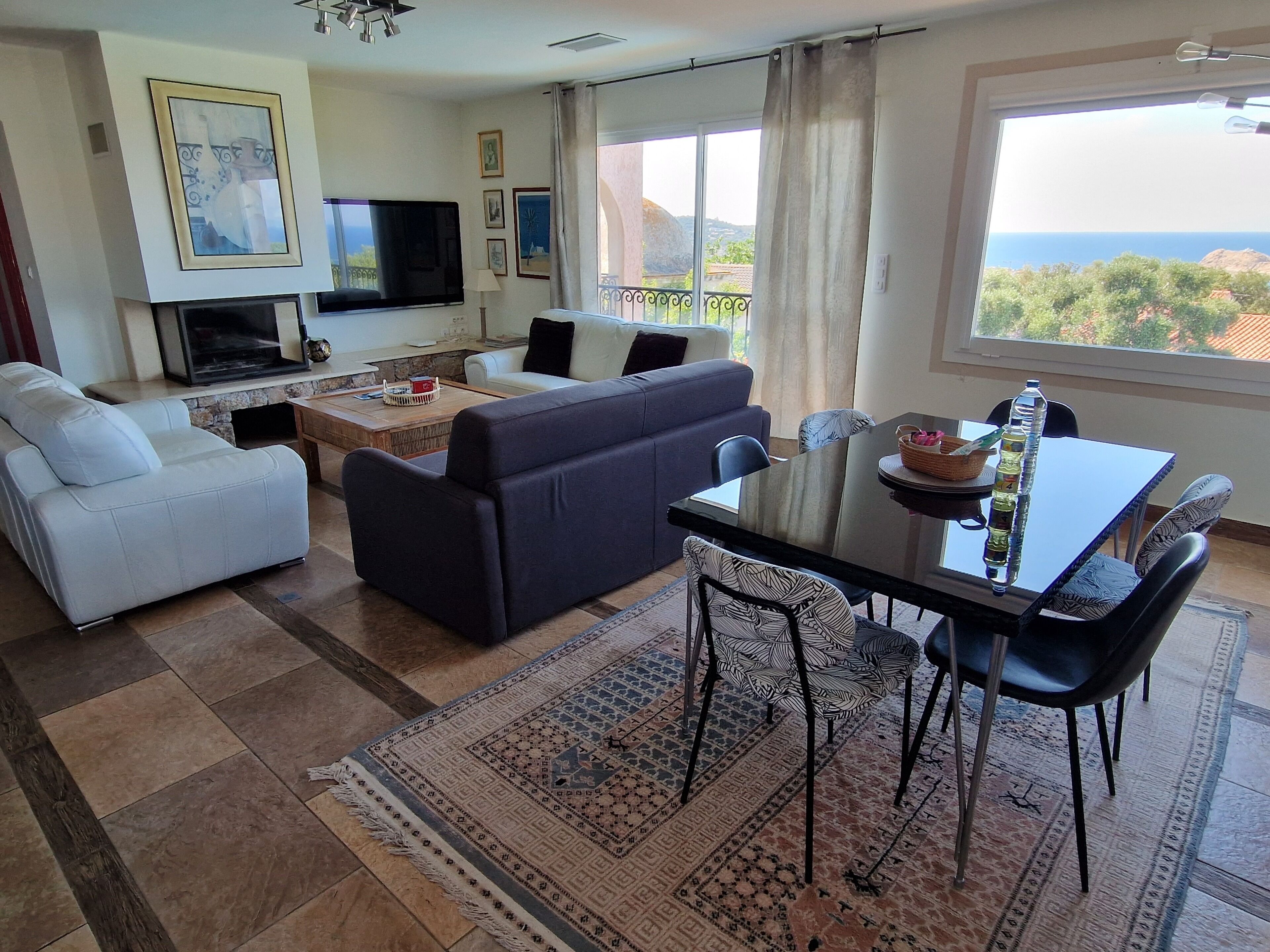 A living room with a sofa, a coffee table, a TV, and a dining area with a table and chairs.