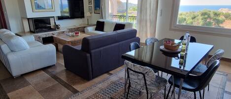 A living room with a sofa, a coffee table, a TV, and a dining area with a table and chairs.