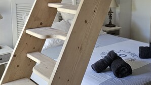 Uma escadaria espiral de madeira em quarto de hotel, com uma cama e um letreiro na parede que diz "VACANCES".
