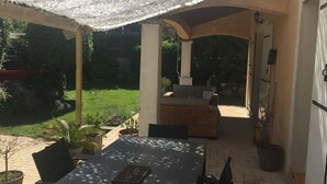 An outdoor patio area with a covered seating area, a table, and a grill.