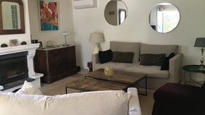 A living room with a fireplace, a sofa, a coffee table, and two round mirrors on the wall.
