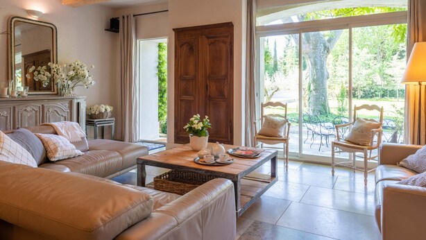 A spacious living room with a large sofa, a coffee table with decorative items, and a view of the outdoors through large windows. - In the Mas des Pampres, Provence is at your fingertips (Cabannes)