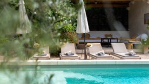 A poolside area with lounge chairs and umbrellas, a covered seating area, and a view of the pool. - In the Mas des Pampres, Provence is at your fingertips (Cabannes)