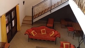 Un espacio habitable amplio con escalera, sofás rojos y techo de madera.