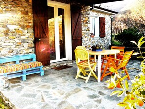 A stone building with a wooden bench and a table with chairs.