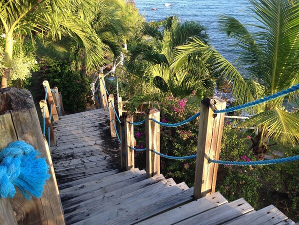 A wooden staircase leading to a beach with a rope barrier.