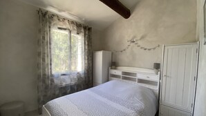Une chambre à coucher comprenant un lit, une armoire, une fenêtre avec des rideaux et une étagère fixée au mur.