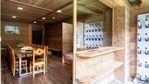 Un intérieur en bois comprenant une table à manger, des chaises, un banc, un comptoir et un porte-bouteilles fixé au mur.