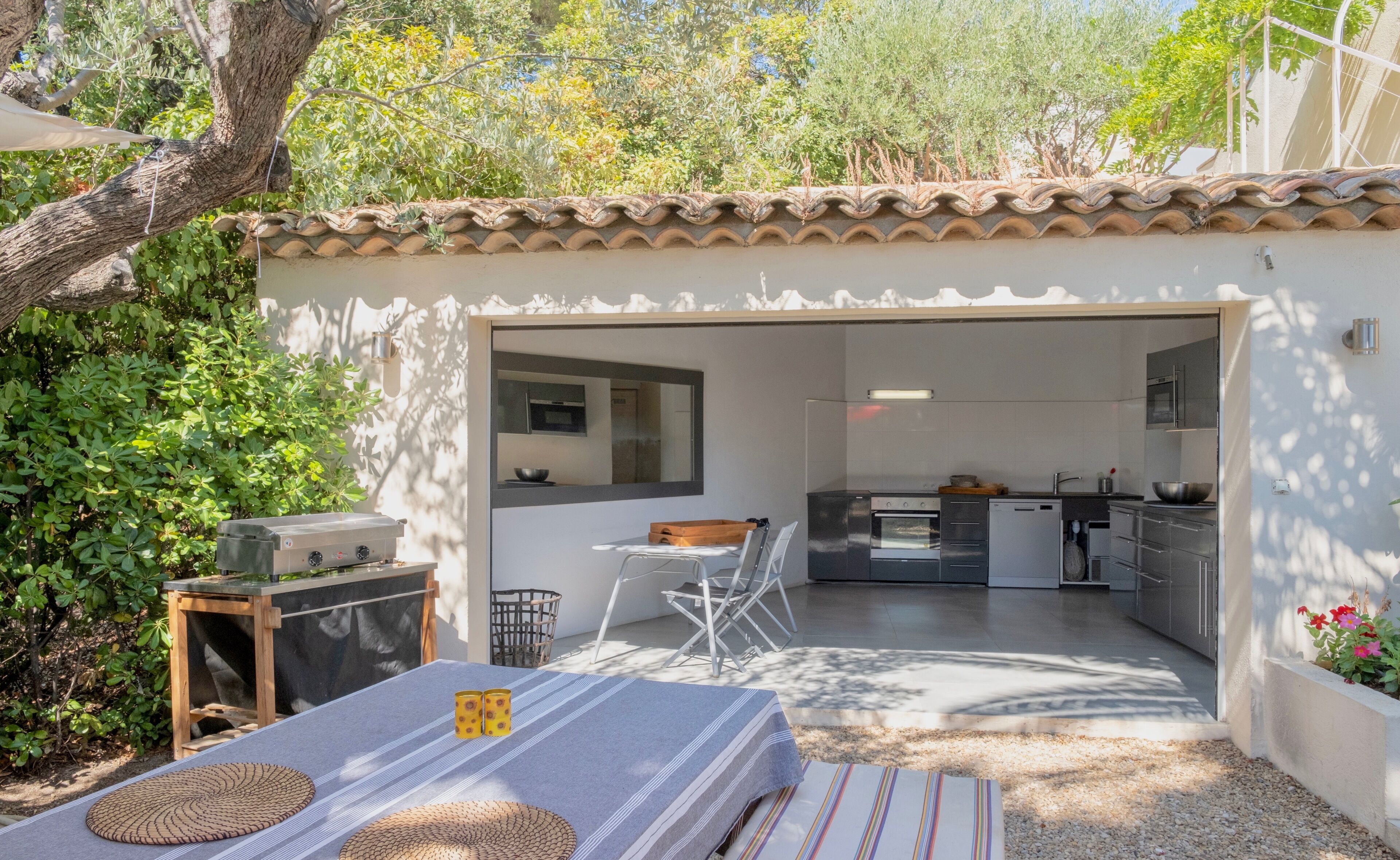A compact kitchen with modern appliances, a dining area with a table and chairs, and a small outdoor seating area with a table and cushions.