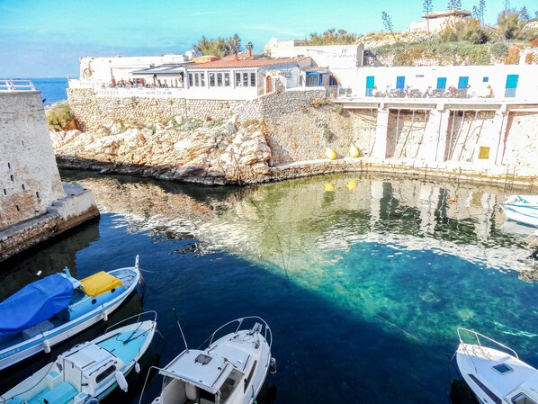 Un porto turistico con barche ormeggiate, un muro in pietra e edifici con porte blu.