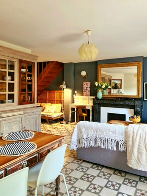 A cozy room with a fireplace, a dining table with chairs, a sofa, and a staircase.
