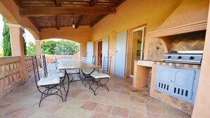 An outdoor patio with a table and chairs, a grill, and a tiled floor. - Luxury villa with view of the putting green - Gulf of Saint-Tropez (Sainte-Maxime)