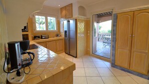 A kitchen with a coffee maker, a refrigerator, and wooden cabinets. - Luxury villa with view of the putting green - Gulf of Saint-Tropez (Sainte-Maxime)