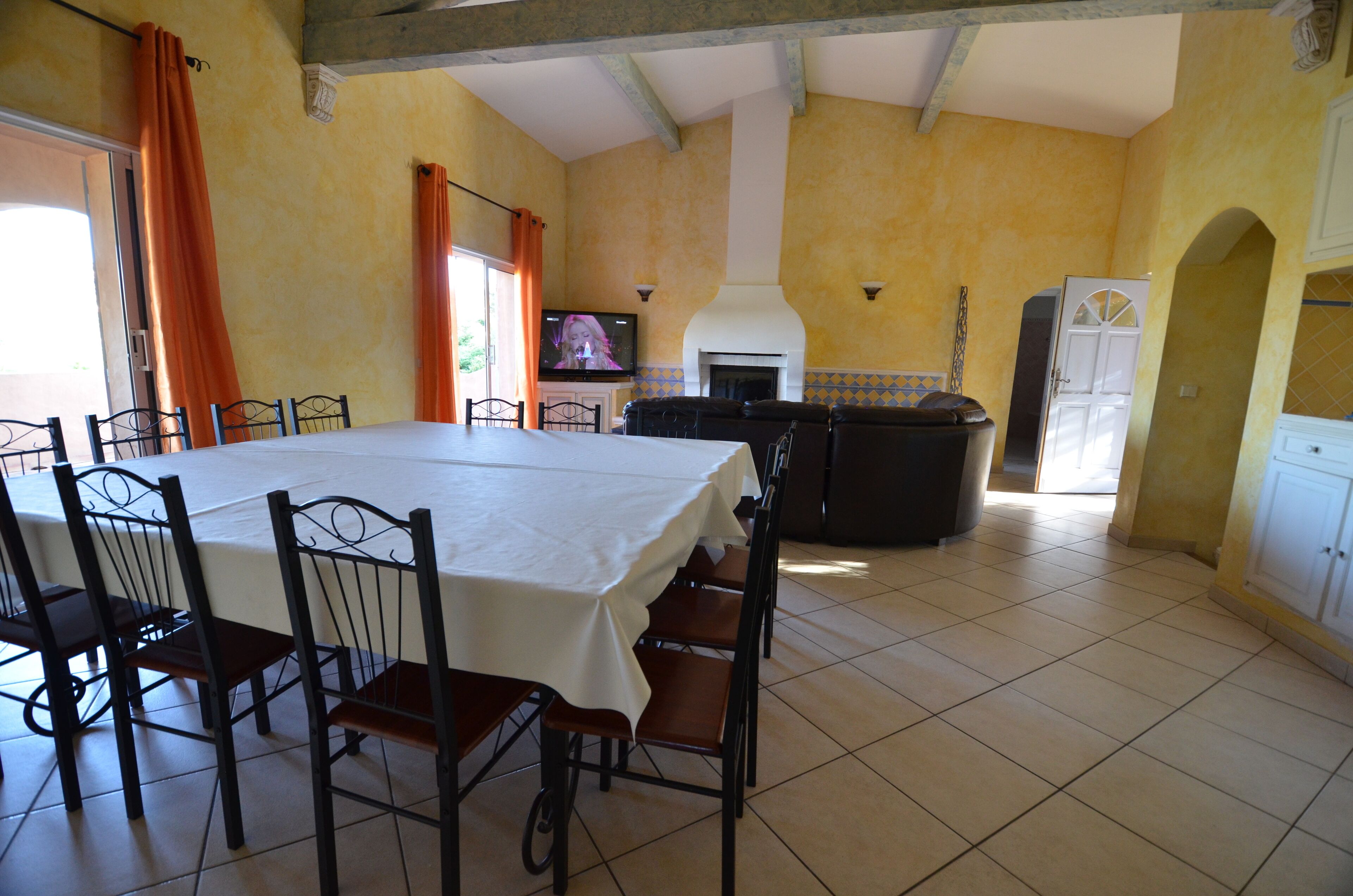 Un coin repas avec une table dressée pour six personnes, des chaises, un téléviseur et une cheminée.